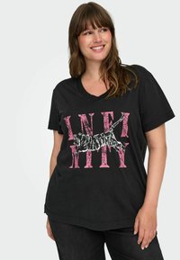 Zwart katoenen T-shirt met een V-hals, een losse fit en een grafisch ontwerp met "INFINITY" in het roze en een zwart-wit gestreepte kattenillustratie.