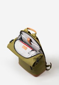 Zaino verde oliva con una maniglia in pelle beige, caratterizzato da un interno a scacchi grigi, una tasca con zip rossa e spallacci regolabili.