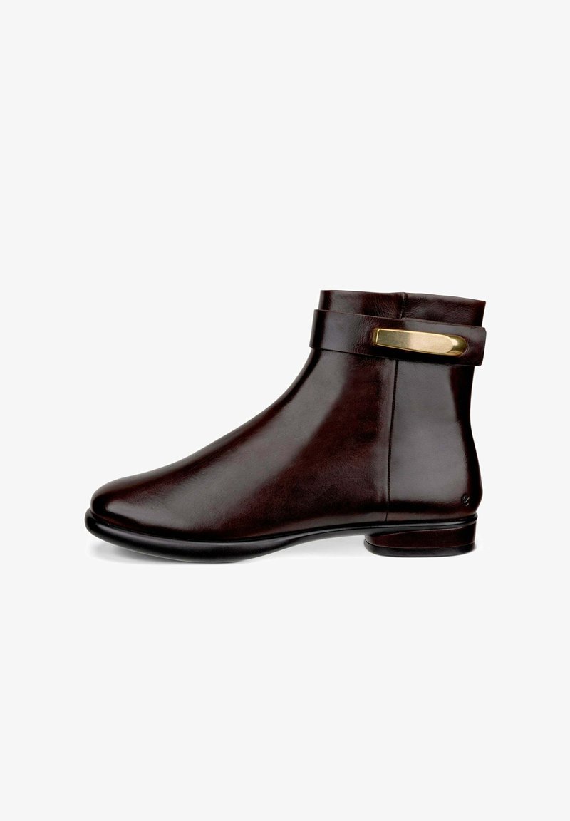 Bottine en cuir marron avec un bout rond, une sangle sur le côté et un accent en métal doré, texture lisse et petit talon.
