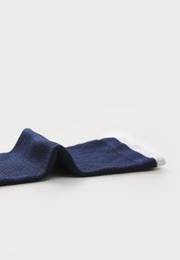 Calcetín azul marino hecho de tejido texturizado, con una franja blanca en el puño y un diseño sin costuras para mayor comodidad.