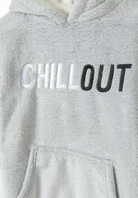 Grijze fleece hoodie met "CHILL OUT" geborduurd in verschillende tinten wit en zwart. Heeft een voorzak en een zachte textuur.