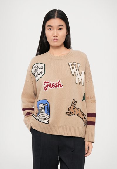 Beige strikkegenser med fargerike broderte lapper, inkludert tekst og et kanindesign. Lange ermer med burgunderstriper ved mansjettene.
