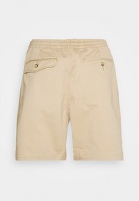 Shorts en coton beige avec taille élastique, deux poches arrière ; la poche gauche est munie d'un rabat à bouton, la poche droite se ferme par un bouton.