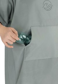 Graues Stoffkleidungsstück mit großer Fronttasche, die eine transparente grüne Flasche hält. Einfaches Design mit glatter Textur und minimalen Akzenten.