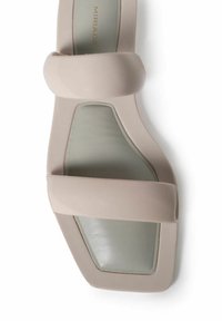 Sandalia beige con un acabado brillante, que presenta dos tiras anchas y una forma cuadrada. La plantilla es de color verde claro, destacando la estética moderna del diseño.