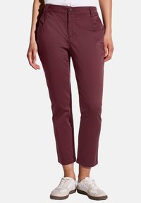 Burgundy stretchbyxor med framfickor, blixtlås och en enda knappst�ängning. Tillsammans med vita sneakers för en avslappnad look.