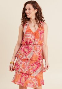 Blumenmusterkleid in Pink, Orange und Creme mit geschichteten Rüschendetails, V-Ausschnitt und ärmellosem Design. Mit aufwendigen Druckdetails.