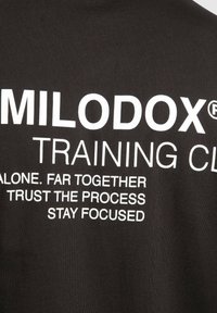 Sort bomulds T-shirt med hvid tekst, der står "MILODOX® TRAINING CLUB" samt motiverende sætninger i et moderne skrifttype.