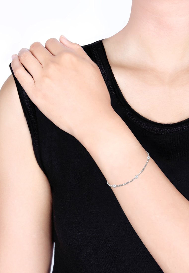 Bracelet en argent avec de petits accents circulaires, présenté sur un poignet. La chaîne est délicate avec des embellissements régulièrement espacés.