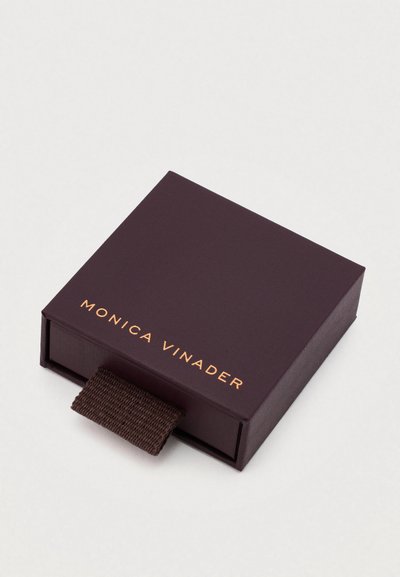 Temno vijolična pravokotna škatla z teksturirano površino, ki vsebuje zlat logo "MONICA VINADER" in rjav tekstilni povlečni trak.