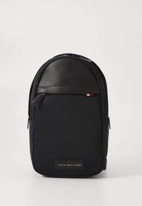 Schwarzer Rucksack aus strapazierfähigem Nylon mit abgerundetem Oberteil, Fronttasche und Lederakzenten. Verfügt über ein kleines Logo-Patch und Reißverschlüsse.