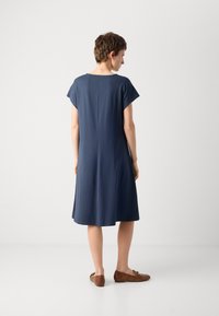 Navy blue dress with short sleeves, a round neckline, and a flared silhouette, made of soft fabric. Brown flats are also visible.