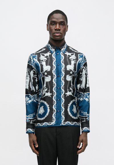 Čierno-modrá košeľa s dlhým rukávom obsahujúca zložité biele vzory s postavami, ornamentmi a detailnými akcentmi; zapínanie na gombíky vpredu.