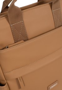 Borsa tote in ecopelle marrone con cuciture rinforzate, tasca frontale e manici piatti. Texture liscia con dettagli hardware minimi.