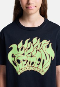 Μαύρο βαμβακερό μπλουζάκι με μια ζωντανή γρ�αφική παράσταση έμπνευσης από φλόγα σε έντονο πράσινο χρώμα, με το κείμενο "ELEMENT SKATEBOARDS" σε αντίθεση με καφέ περίγραμμα.