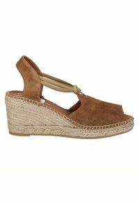Sandalias con cuña de ante marrón, con una correa de tobillo elástica, punta abierta y suela de yute trenzado, presentando un diseño redondeado y un acabado texturizado.