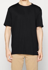 T-shirt nera in cotone con scollo a giro, maniche corte e vestibilità rilassata. Presenta un design semplice senza motivi o accessori visibili.