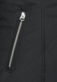 Černá tkanina se hladkým povrchem má výrazný stříbrný zip na boku. Zip má charakteristickou kovovou táhlo.