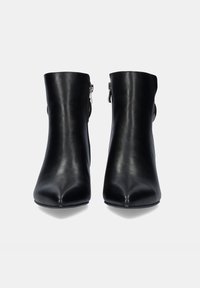 Botas de cuero negras hasta el tobillo con punta afilada, textura suave y detalles de cremallera lateral, con un ajuste ceñido alrededor del tobillo.