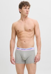 Graue Boxershorts mit angepasstes Design, elastischem Bund, der "JACK & JONES" in pink und blauer Schrift zeigt. Glatte Stofftextur.