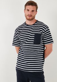 Navy en witte gestreepte t-shirt met korte mouwen, een ronde hals en een borstzakje. Zacht katoenen stof met een relaxte pasvorm.