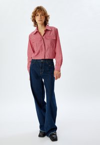 Rød og hvid stribet cropped skjorte med to brystlommer, parret med mørkeblå vide jeans og sorte lædersko.