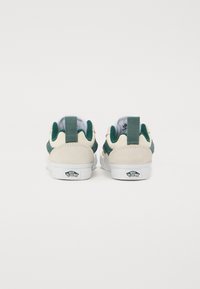 Sneakers z beżową zamszową cholewką i zielonymi akcentami z materiału. Posiadają białą gumową podeszwę i zapiętek z logo. Prosty design, niski krój.