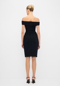 Abito nero off-the-shoulder con silhouette aderente, orlo a ginocchio, tessuto texturizzato e dettaglio con zip sulla schiena.