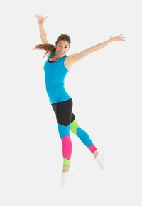 Heled sinine tank top, mis on kombineeritud mustade legginsitega, millel on roosa, sinine ja roheline geomeetriline muster. Mudel kannab valgeid spordijalatsite.