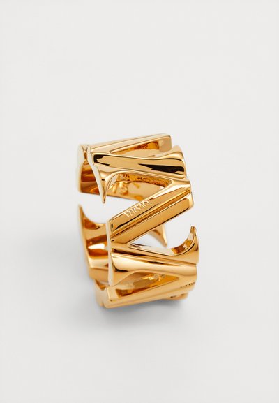Goldfarbener Metallring mit geometrischem Design, der kantige Formen und eine glänzende Oberfläche aufweist. Graviertes Logodetail auf dem inneren Band.
