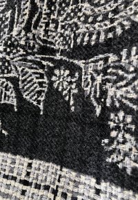 Tessuto nero intrecciato con intricati motivi grigi, caratterizzato da texture e design variabili. Motivi geometrici e floreali notevoli in tutto.