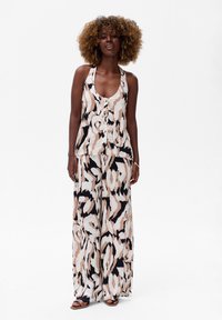 Haut sans manches à imprimé floral avec détail de boutons, associé à un pantalon large. Les couleurs comprennent pêche, noir et crème, avec une texture lisse.