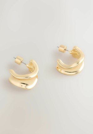 Zelta krāsas metāla riņķa auskari ar gludu, spīdīgu virsmu. Ir izliekta forma un aizdare ar spiedpogu drošai valkāšanai.