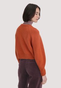 Gekürzter oranger Pullover aus Strickstoff mit gerippten Bündchen und Saum. Verfügt über einen runden Ausschnitt und Nahtdetails auf der Rückseite.