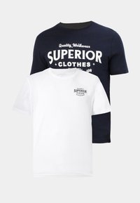 Twee t-shirts: een marineblauwe met witte grafische tekst "SUPERIOR CLOTHES," en een witte met een kleiner marineblauw logo. Beiden zijn van katoen en hebben een ronde hals.