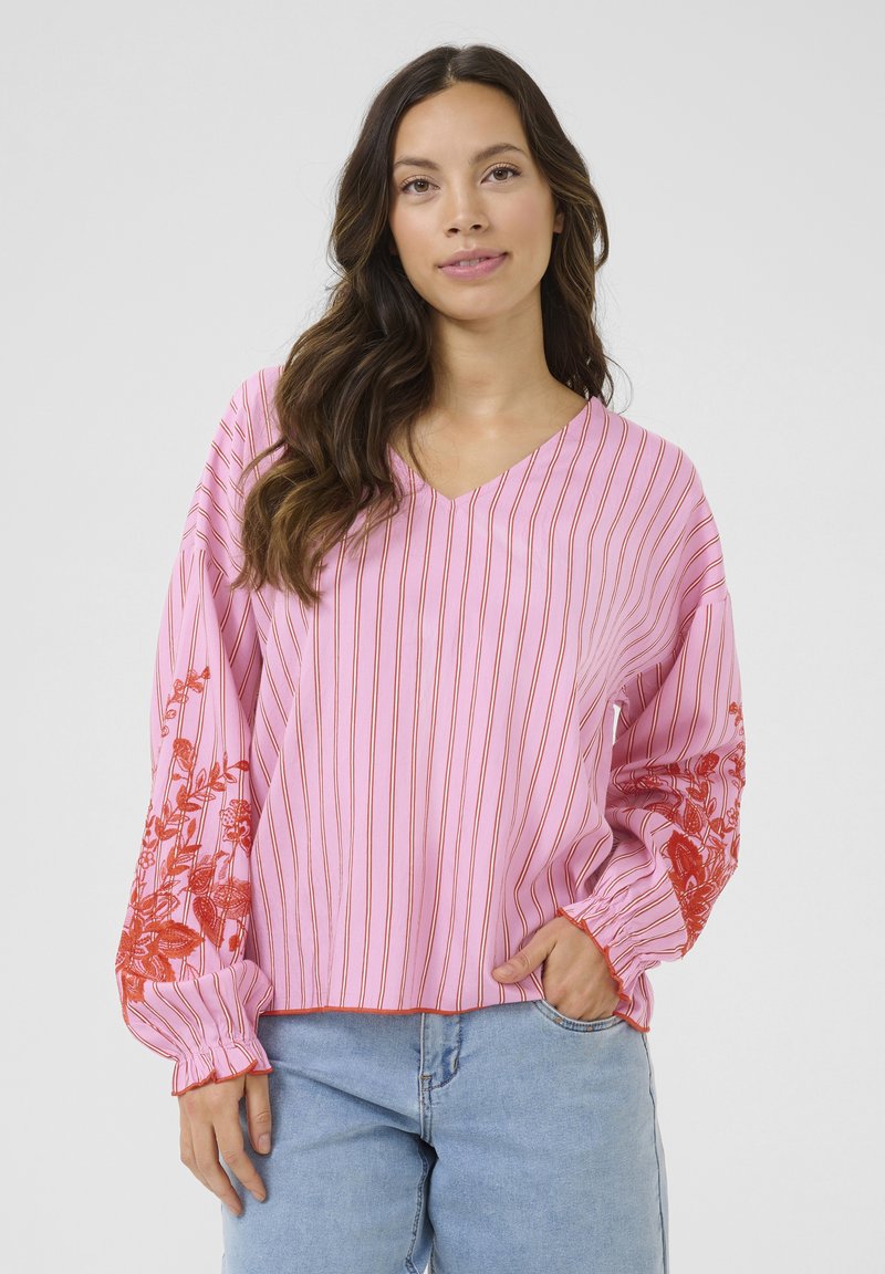 Rosa gestreifte Bluse mit langen Ärmeln, die lebendige rote Blumenstickerei an den Ärmeln und ein V-Ausschnitt-Design aufweist. Glatte Textur.
