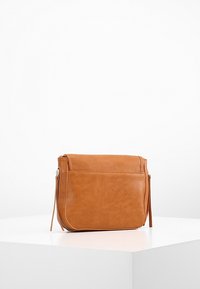 Tan læder crossover taske med en glat overflade, lynlåslukning og en frontlomme; rektangulær form med detalje af sidekvast.