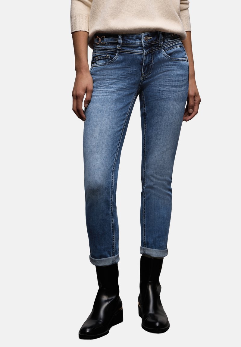 Jean en denim bleu clair présentant une coupe droite, des revers retroussés, un design à cinq poches et des détails de couture subtils à la taille.