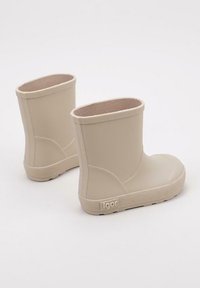 Bottes en caoutchouc beige avec une finition lisse, un bout rond et une semelle texturée. Design court avec un simple revers en haut et un logo sur le côté.