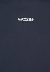 Navy blue sweatshirt with a crew neck, featuring a white rectangular embroidered logo with black cursive text. Smooth, cotton fabric.