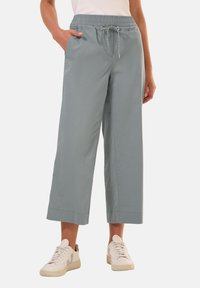 Pantaloni ampi azzurro chiaro con vita elastica, chiusura con cordoncino e tasche laterali, abbinati a sneakers bianche.