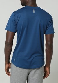 Kortärmad marinblå t-shirt i mjukt och lätt material. Har en liten reflexdetalj på baksidan och en logotyp på vänster ärm.