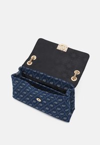 Niebieska torebka z pikowanego materiału z wzorem diamentów i logo, złoty łańcuszek na ramię oraz otwarta czarna podszewka z magnetycznym zapięciem.