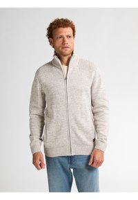 Kudotusta vaaleanharmaasta neuletakista, jossa on vetoketju edessä. Ominaisuudet ribbireunat kauluksessa ja hihansuissa sekä kaiken kaikkiaan teksturoitu kuvio.