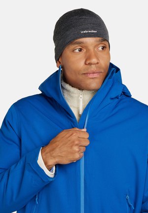 Chaqueta azul de hombre para exteriores con cierre frontal y capucha; cuenta con un suave forro de felpa color crema y un gorro gris con logo.