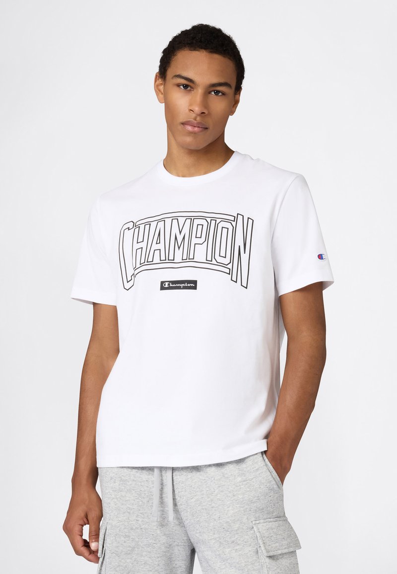 T-shirt en coton blanc avec un grand logo noir "CHAMPION" sur la poitrine, manches courtes et coupe décontractée.