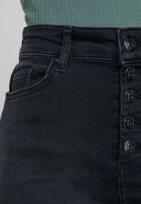 Svarta högmidjade jeans i denim har en femknapps-stängning, framfickor och subtila sömnadsdetaljer längs midjebandet.