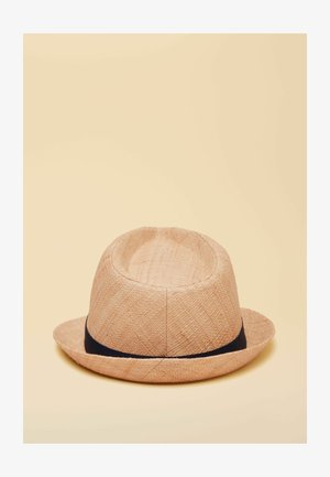 Hellbrauner geflochtener Fedora-Hut mit einem schwarzen Band am unteren Rand, vor einem schlichten beigen Hintergrund.