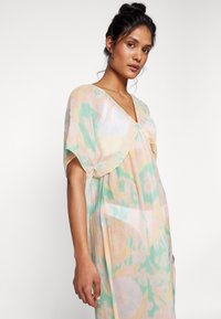 Vestido ligero y fluido con escote en V. Presenta colores pastel: verde menta, durazno y amarillo. Mangas cortas con diseño de murciélago y un corte holgado.