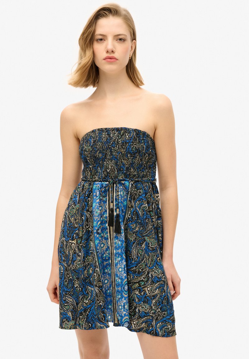 Robe sans bretelles avec un motif cachemire bleu et noir, corsage smocké et cordon réglable avec des pompons à la taille.